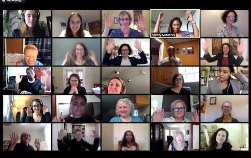 25 video conference participants smile. Several participants are raising up their hands.