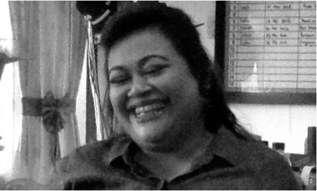 A black-and-white photograph of a woman with black hair laughing. 